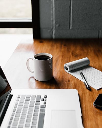 Ordinateur portable, bloc note avec stylo et tasse de café sur un bureau